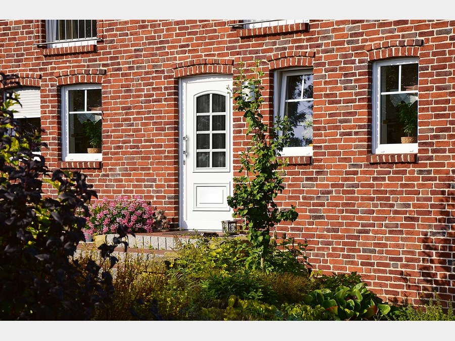Weiße klassische Haustür, Backsteinhaus mit Efeu